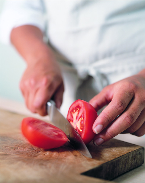 Cutting tomato with professionally sharpened kitchen knife